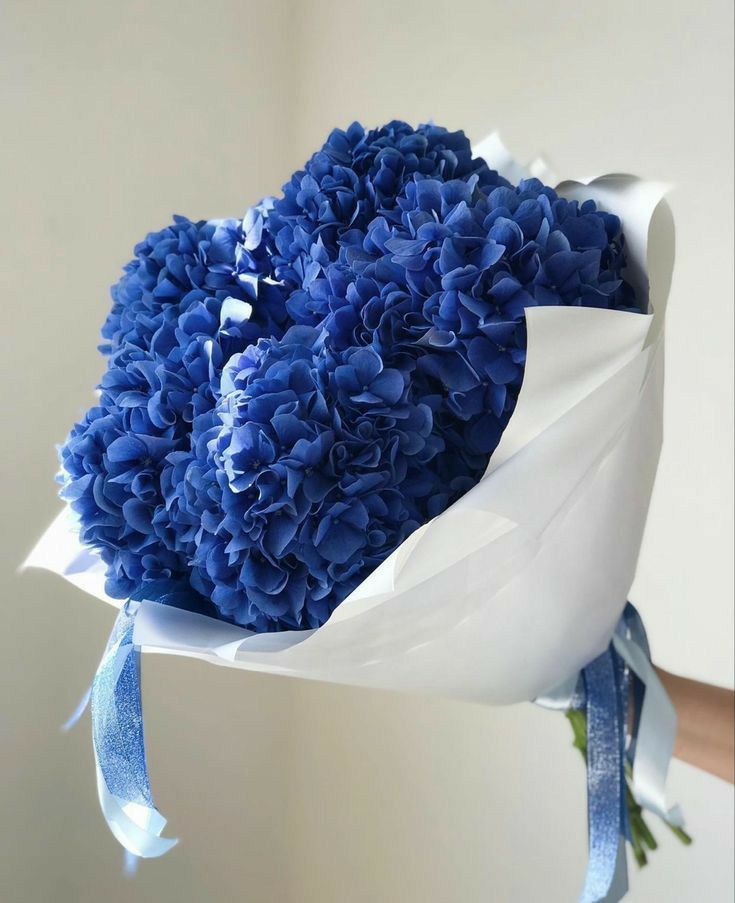 a bouquet of blue flowers wrapped in white paper