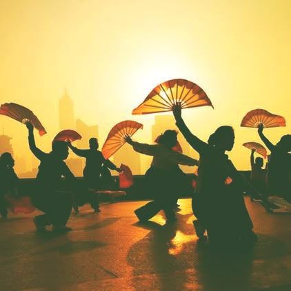 silhouettes of people holding umbrellas in front of the sun on a city street