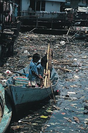 two people in a small boat surrounded by trash