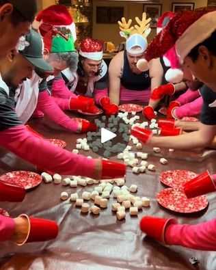 a group of people sitting around a table making heart shaped cookies and marshmallows