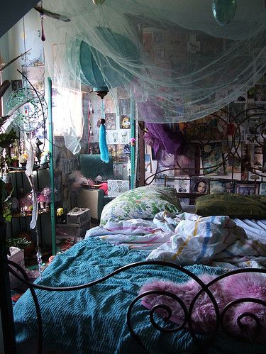 an unmade bed in a cluttered room with mosquito netting