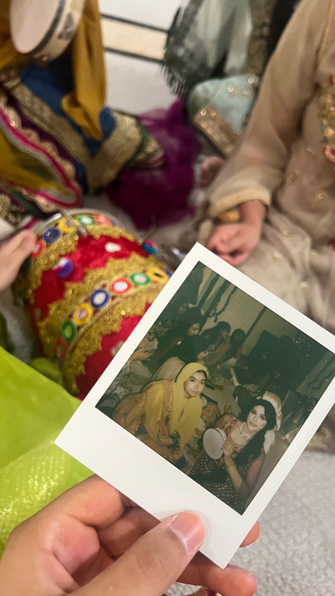 a person holding up a polaroid photo in front of other people sitting on the floor