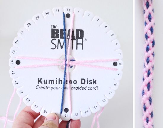 a hand holding a white clock with pink string attached to it