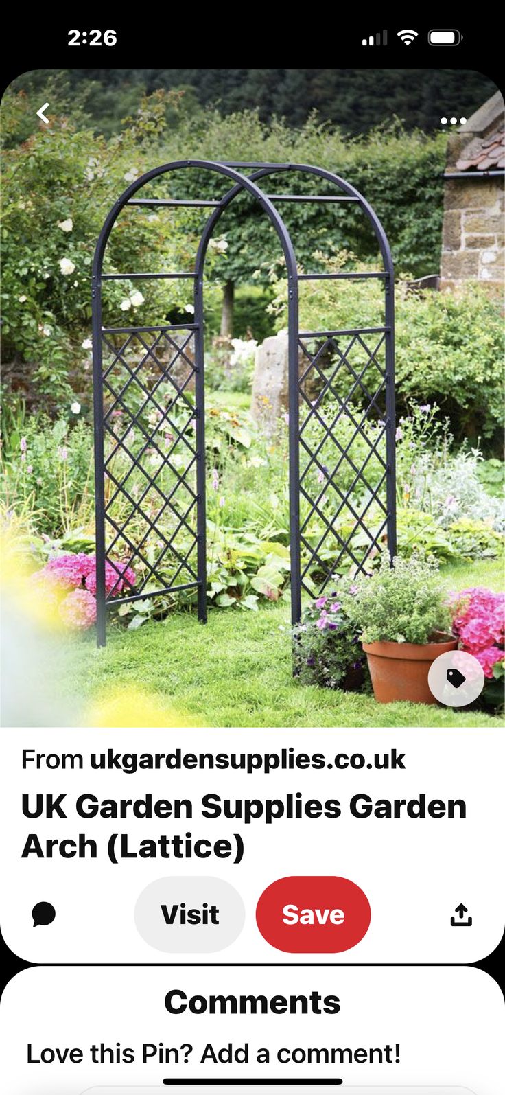 an iron garden arbor in the middle of a flower garden with potted plants and flowers