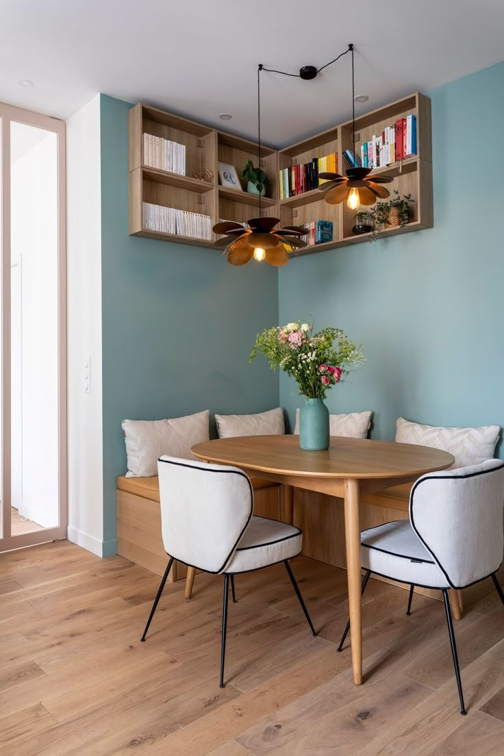 a dining room table and chairs with bookshelves above it