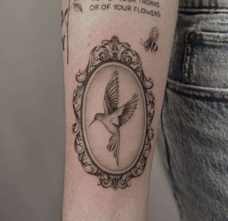 a woman's arm with a tattoo on it that has a bird in the frame