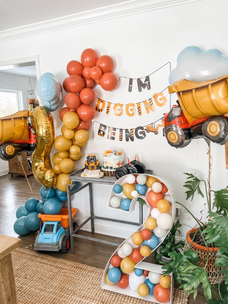 a room filled with balloons and toys in the shape of trucks, cars, and numbers