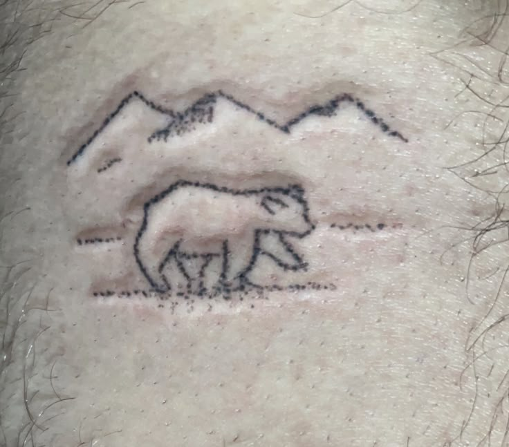 a man with a tattoo on his neck that has two horses in the grass and mountains behind him