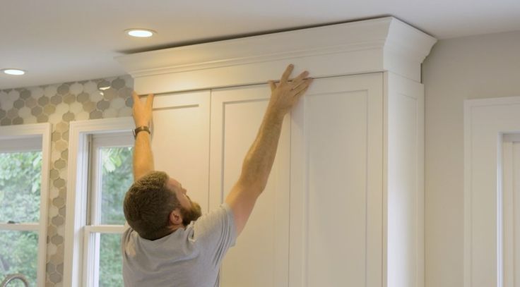 a man that is standing up in the air with his hands on top of a cabinet