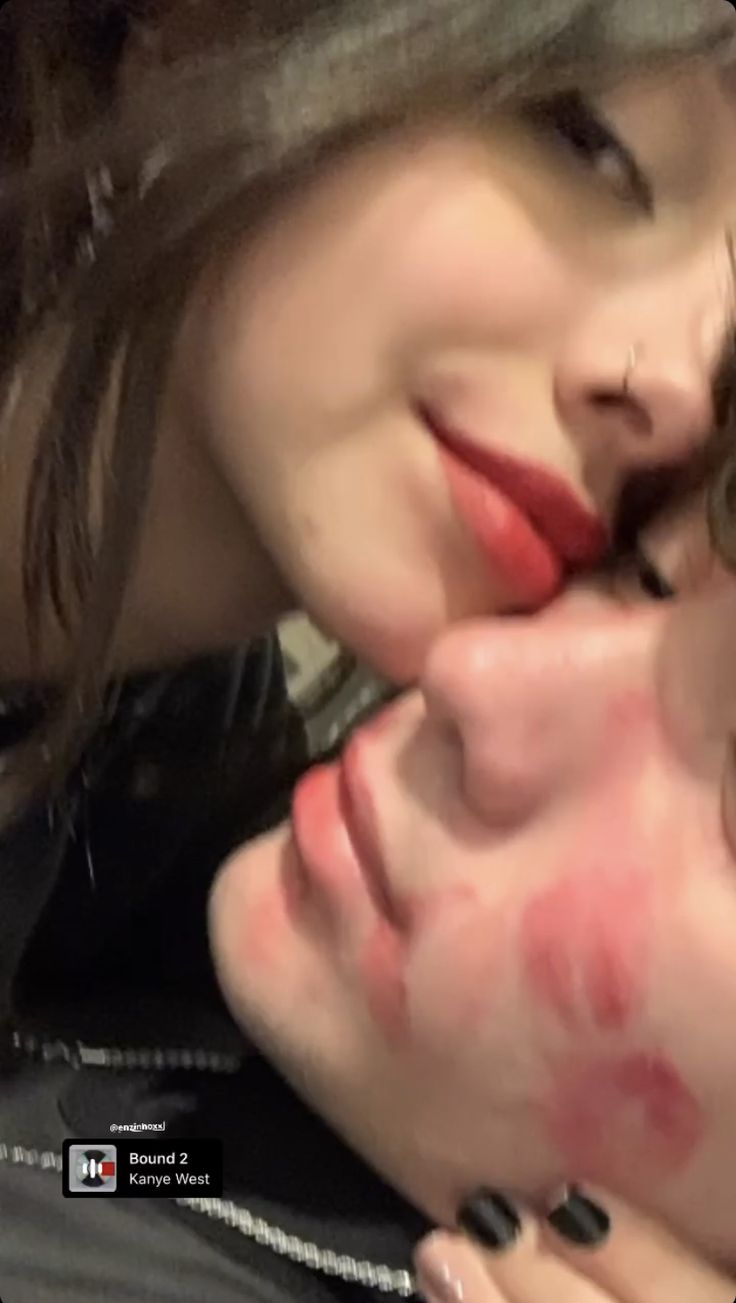 two women with red lipstick on their faces and one is kissing the other's cheek