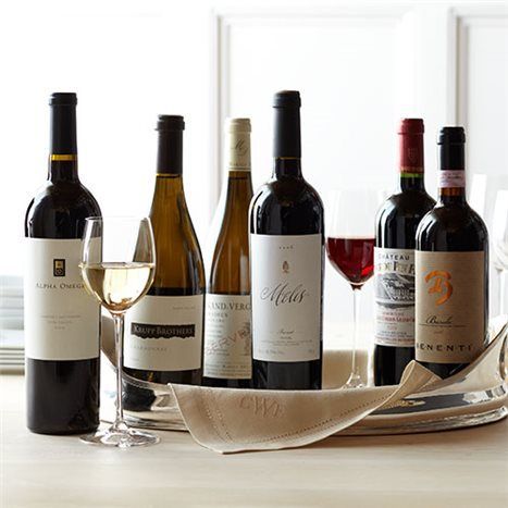 several bottles and glasses of wine sitting on a table with napkins in front of them