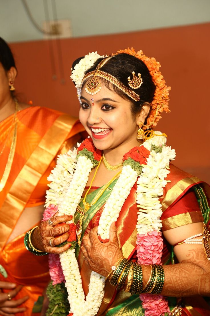 a woman in an orange and yellow sari smiles as she looks at the camera