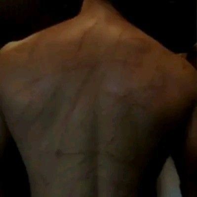 the back of a man's shirtless torso is seen in this image taken from behind