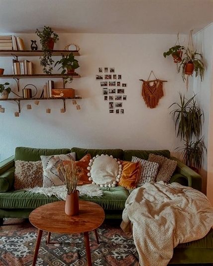 a living room filled with lots of furniture and plants on the wall above it is a green couch