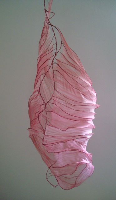 a pink piece of art hanging from a ceiling