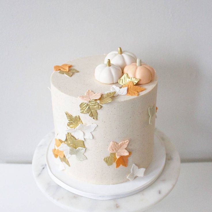 a white cake with gold leaves and pumpkins on top