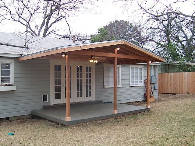 a small gray house sitting in the middle of a yard