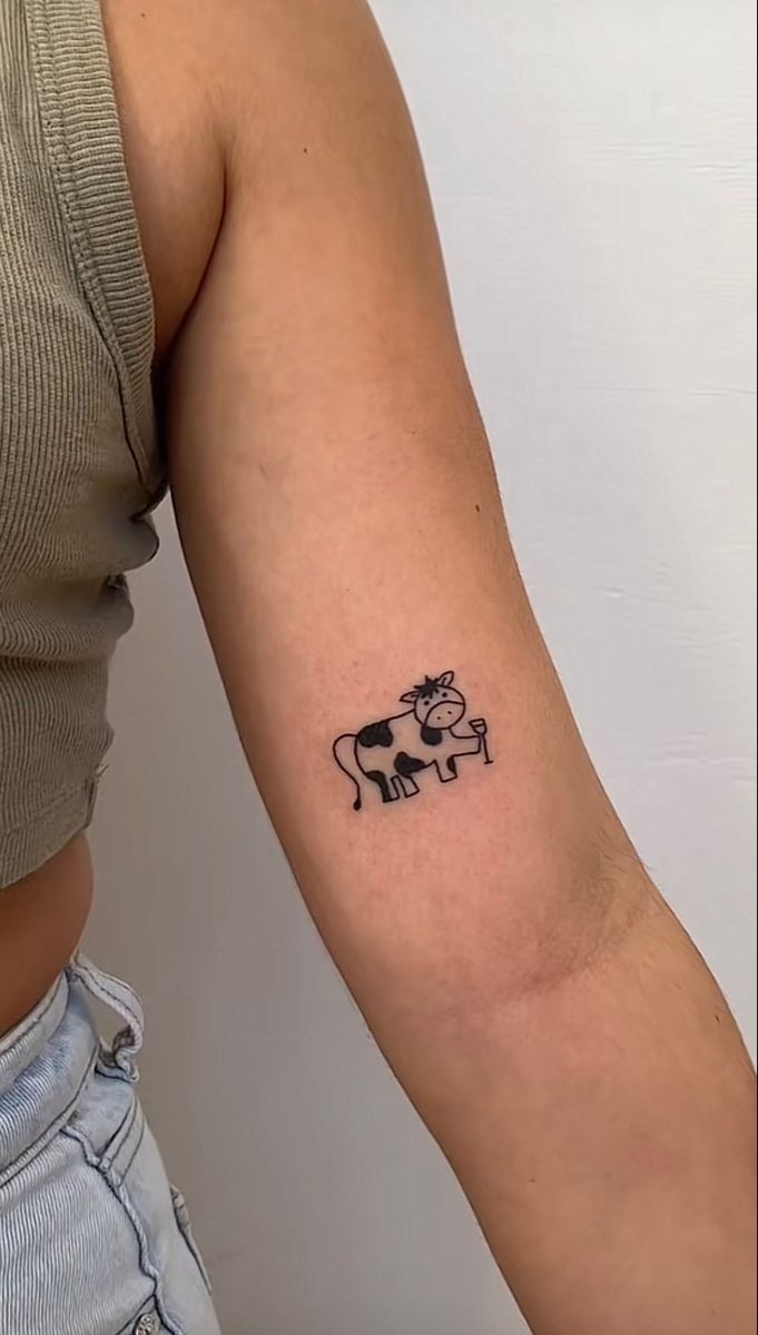 a woman's arm with a cow tattoo on the left side of her arm