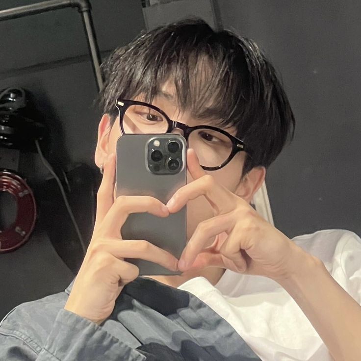 a man taking a selfie with his cell phone in front of him and wearing glasses