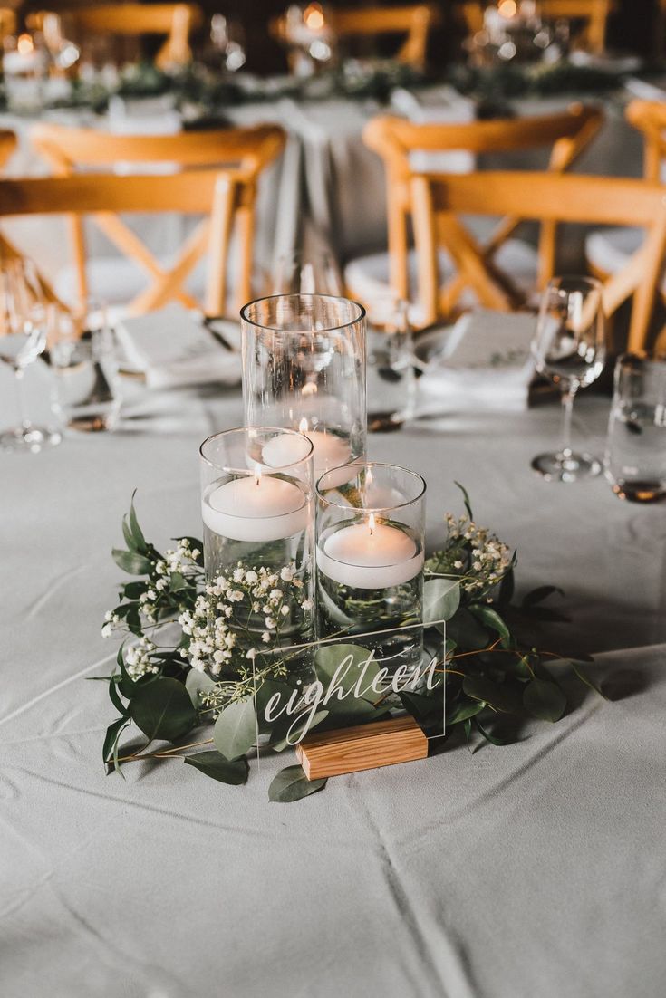 candles and greenery are placed on the centerpieces at this elegant wedding reception