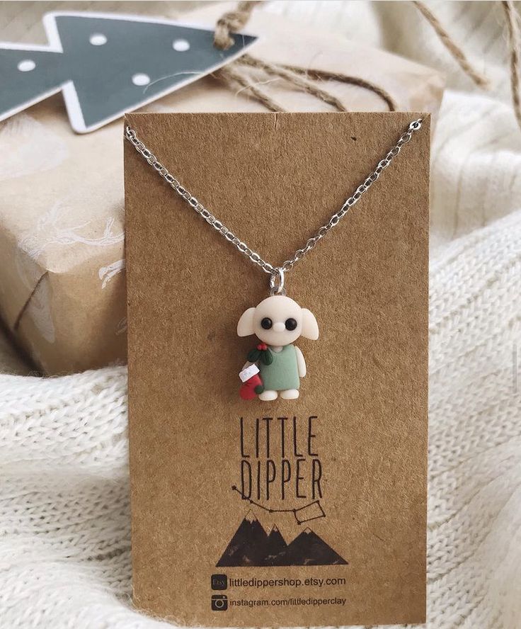 the little puppy necklace is on display in front of a gift box with it's tag