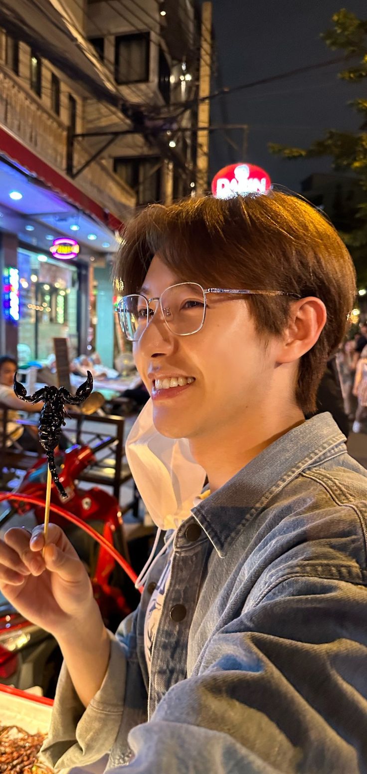 a man with glasses is eating food at an outdoor table in front of a restaurant