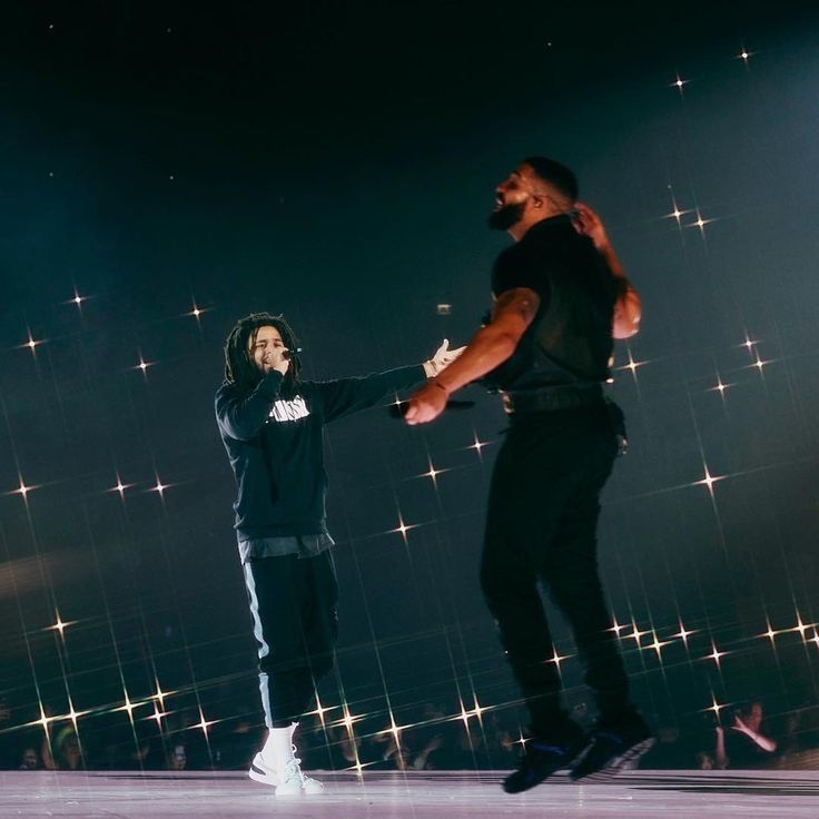 two men on stage with one holding the other's hand