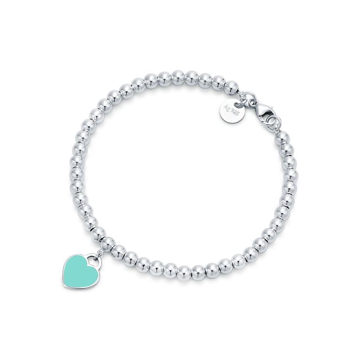 Inspired by the iconic key ring first introduced in 1969, the Return to Tiffany collection is a classic reinvented. An elegant bead bracelet and engraved tag combine to create a simple and timeless design. Sterling silver with Tiffany Blue® enamel finish; Size extra small; Fits wrists up to 5.25"; Beads, 4 mm; Instantly recognizable, the signature Tiffany Blue® hue of this design’s enamel finish has been as iconic as the brand itself since its founding in 1837 | Return to Tiffany® Tiffany Blue® Tiffany Bead Bracelet, Tiffany And Co Bracelet, Tiffany Bracelets, Return To Tiffany, Heart Tag, Silver Bead Bracelet, Tiffany And Co, Mini Heart, Heart Beads