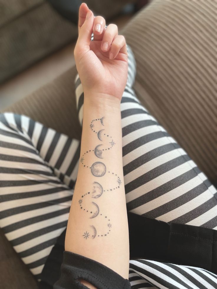 a woman is sitting on the couch with her arm tattoo that says moon and stars