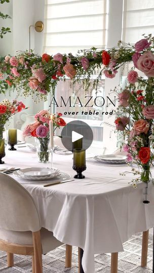 the table is set with white linens, pink flowers and greenery in vases