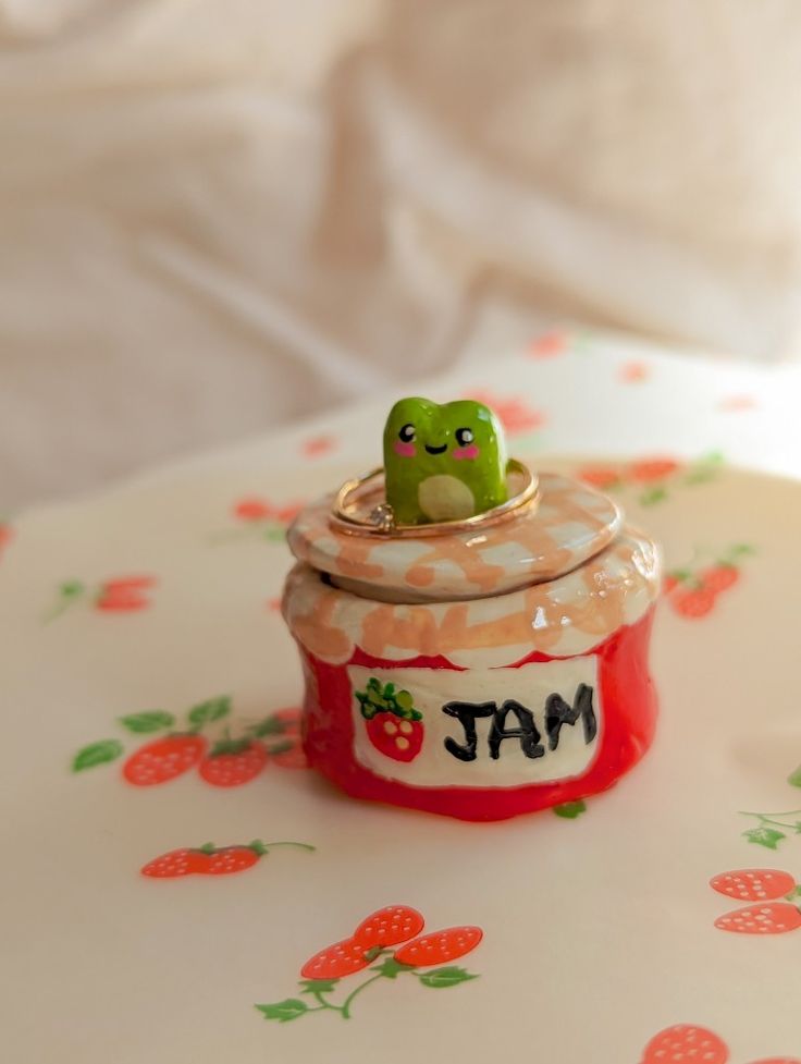 a small toy sits on top of a strawberry jam jar