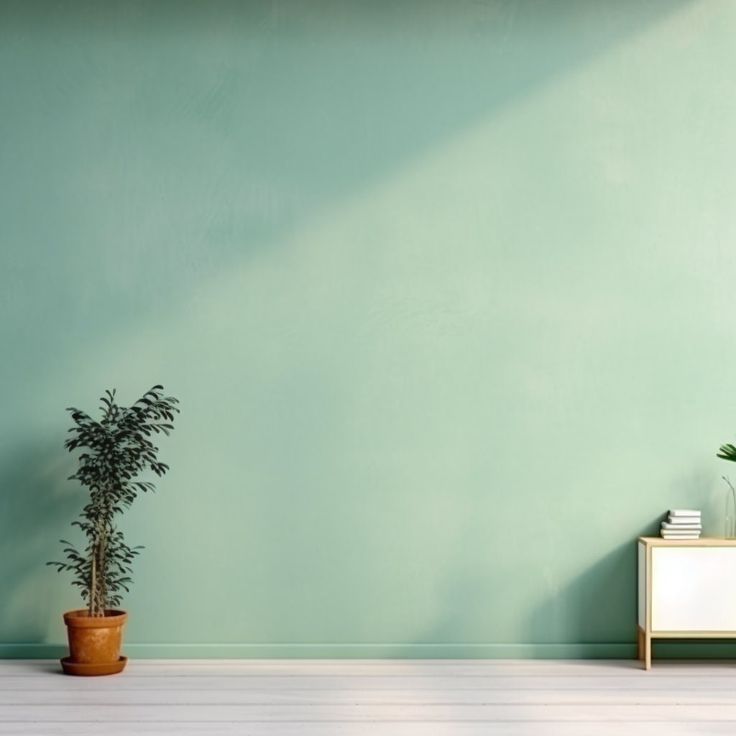 there is a potted plant on the floor in front of a green wall and white cabinet