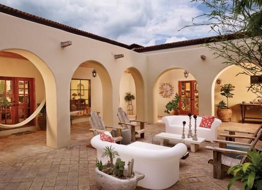 an outdoor living area with white furniture and potted plants on the side of it