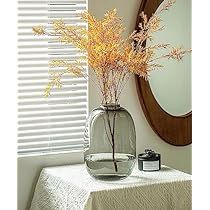 a vase filled with water sitting on top of a table next to a mirror and window