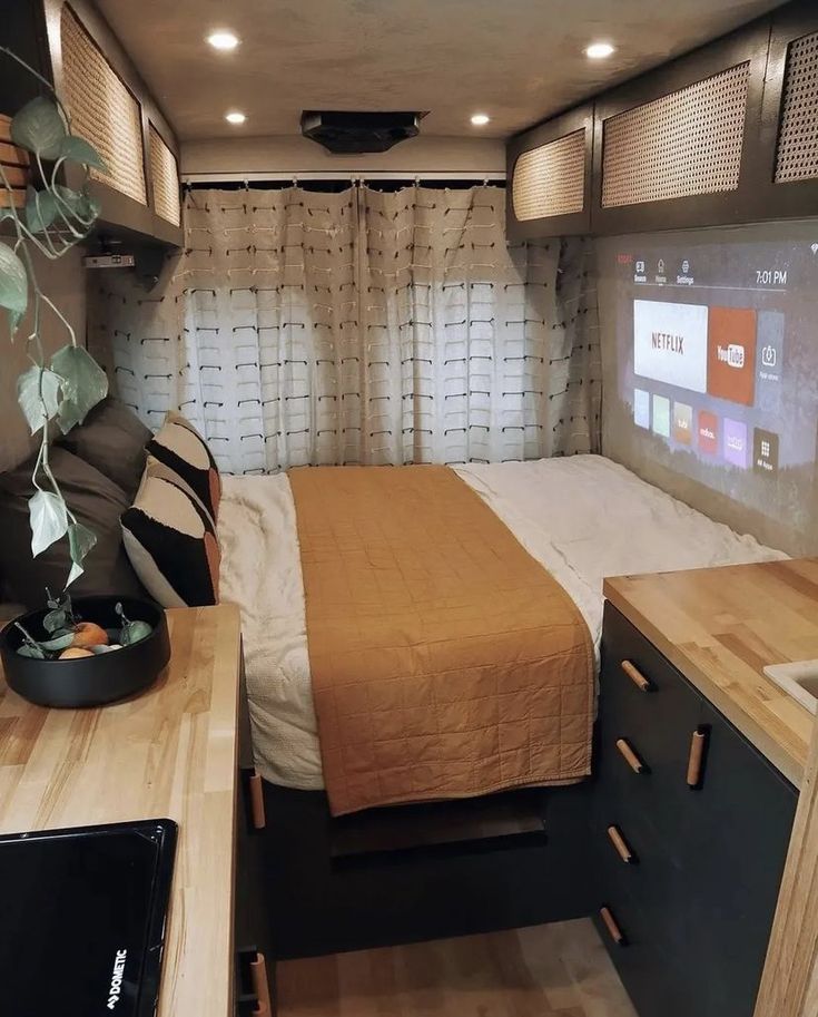 a bedroom with a bed, desk and television in the back ground is lit by recessed lights