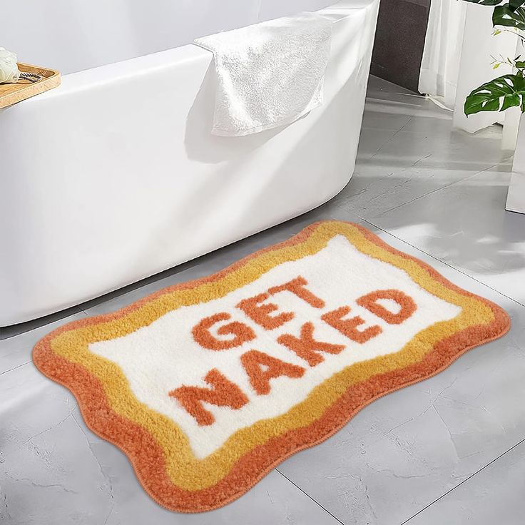 a bathroom rug that says get naked on the floor in front of a bathtub