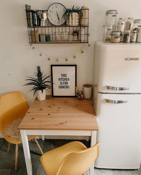 a kitchen table with two yellow chairs and a white refrigerator in the back ground,