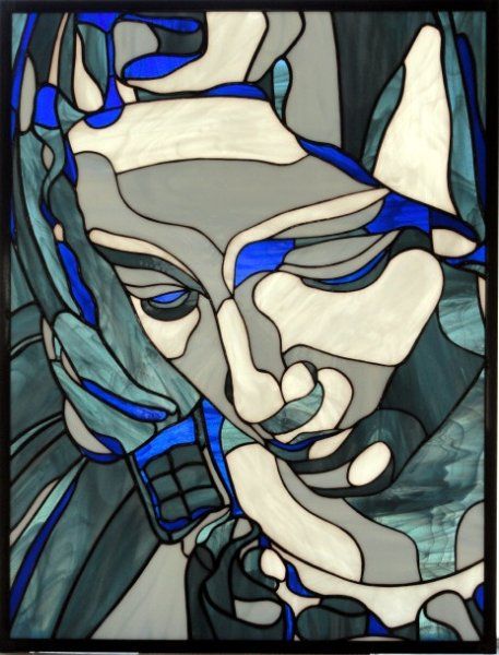 a close up of a stained glass window with a woman's face in blue and white