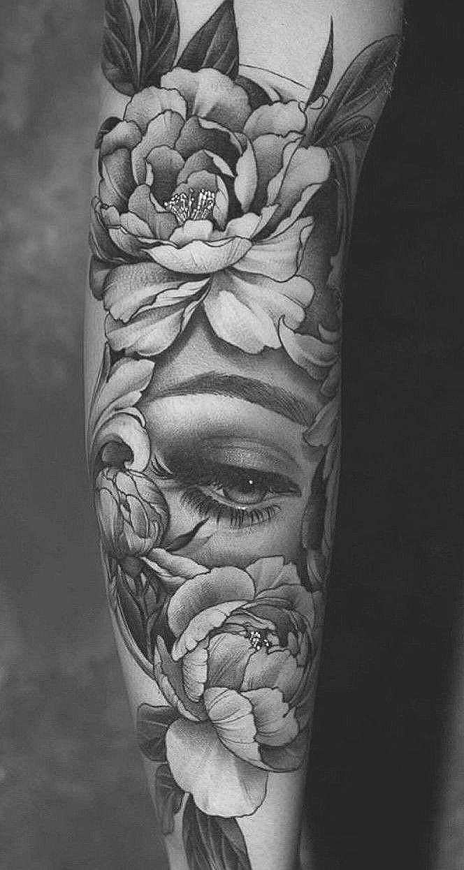 a woman's face with flowers and leaves on her leg, in black and white