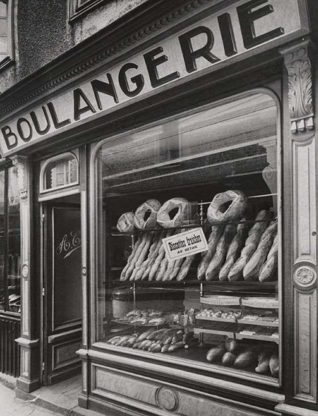 an old black and white photo of doughnuts on display in a store window