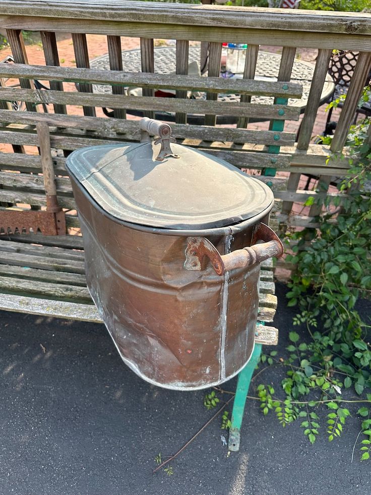 an old metal bucket sitting on top of a wooden bench