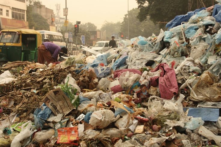 a pile of garbage sitting on the side of a road next to a yellow bus