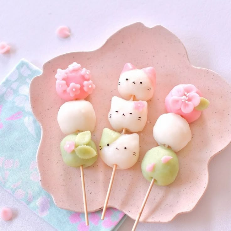 hello kitty lollipops are on a pink plate with green and white candies