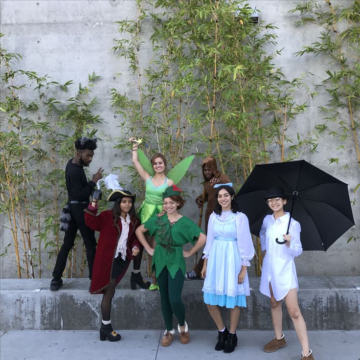 a group of people standing next to each other holding umbrellas and posing for the camera