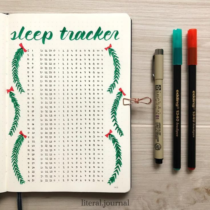 an open notebook with the words sleep tracker written in green on it next to markers and pens