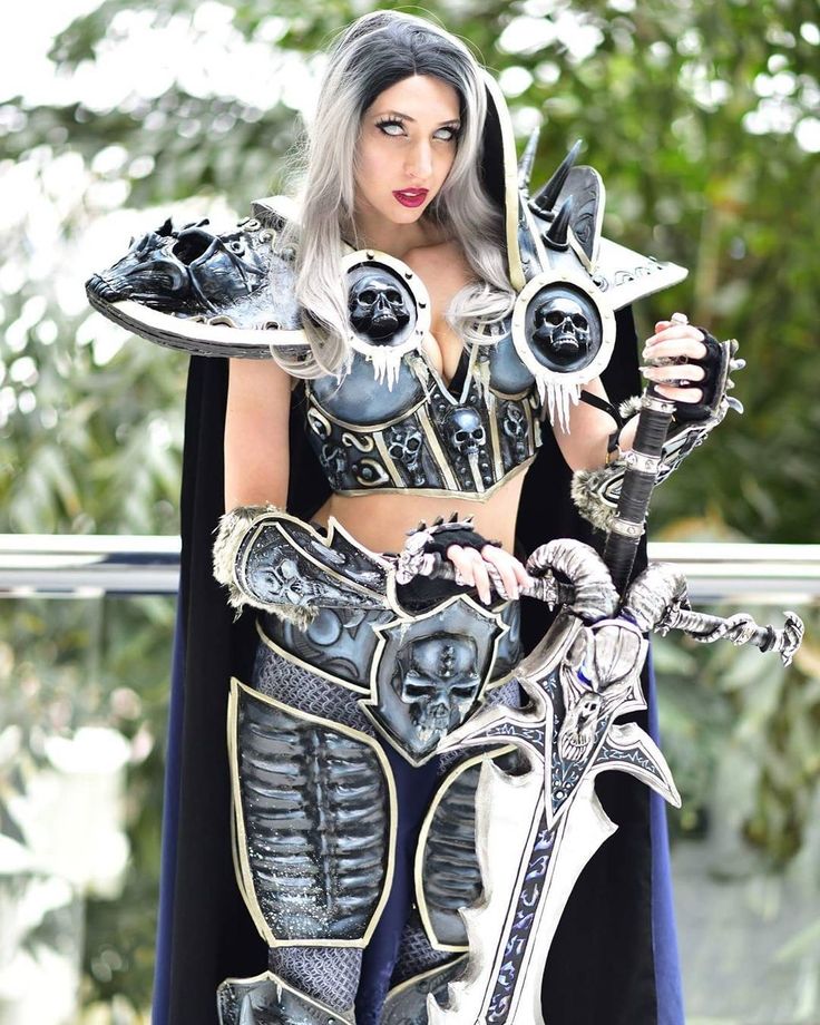 a woman dressed up as a knight holding two silver plates in her hands and wearing a black cape