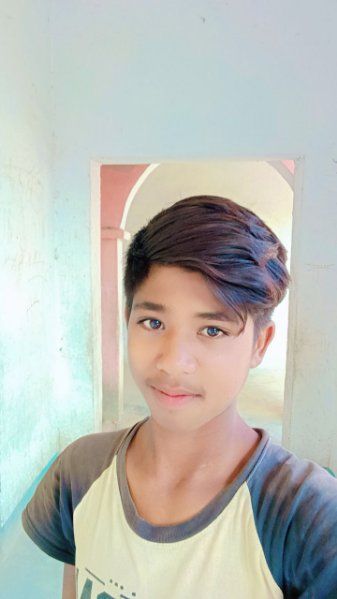 a young boy standing in front of a mirror wearing a white and grey t - shirt