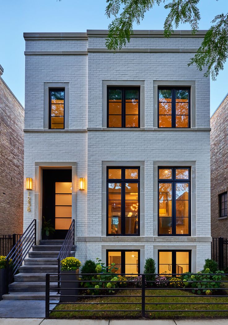 a white brick house with many windows and steps leading up to the front door area