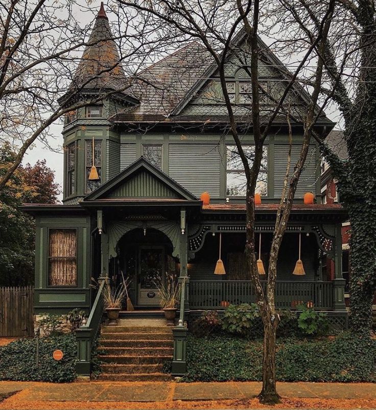 an old victorian house in the fall with pumpkins on the front porch and steps leading up to it