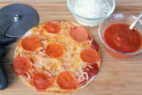 a pepperoni pizza sitting on top of a wooden cutting board next to a knife